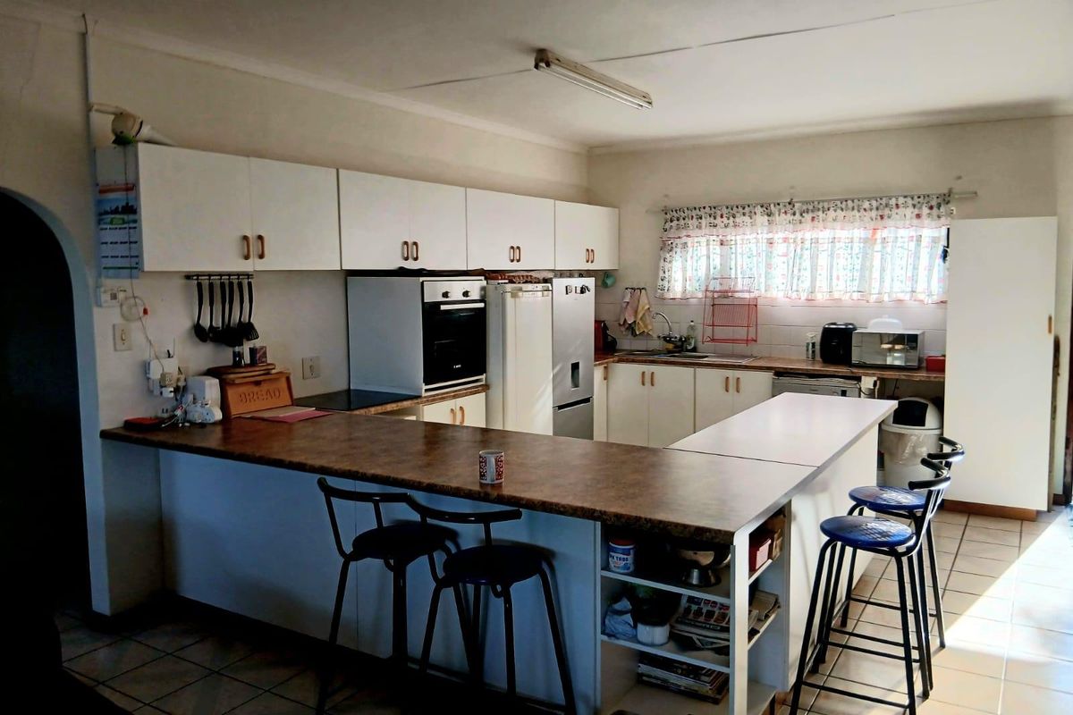 Functional kitchen featuring white cabinetry, laminate countertops, a breakfast bar, and tiled flooring, offering a practical layout with potential for modern updates.