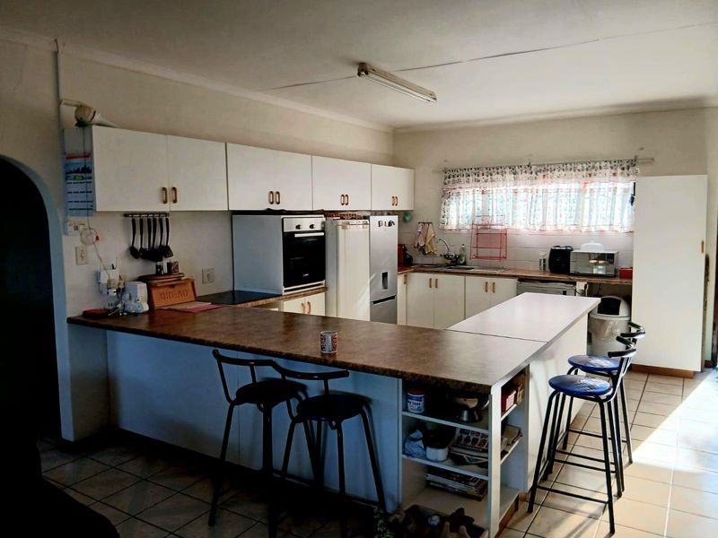 Functional kitchen featuring white cabinetry, laminate countertops, a breakfast bar, and tiled flooring, offering a practical layout with potential for modern updates.