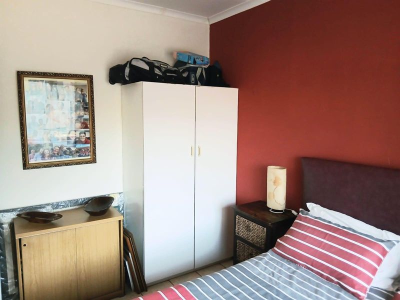 A bedroom featuring a built-in wardrobe and tiled flooring, with a contrasting accent wall.