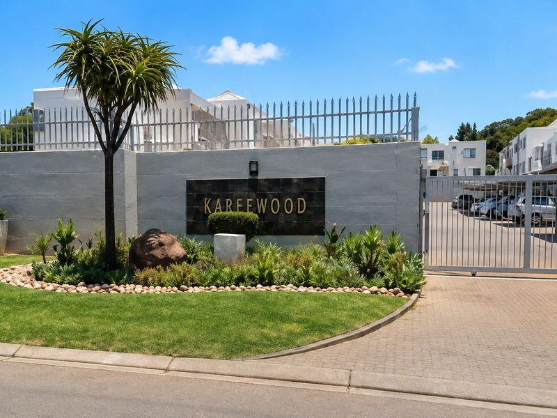 The front entrance of the Kareewood townhouse complex, featuring a secure gated access point, paved driveway, and well-maintained landscaped garden.