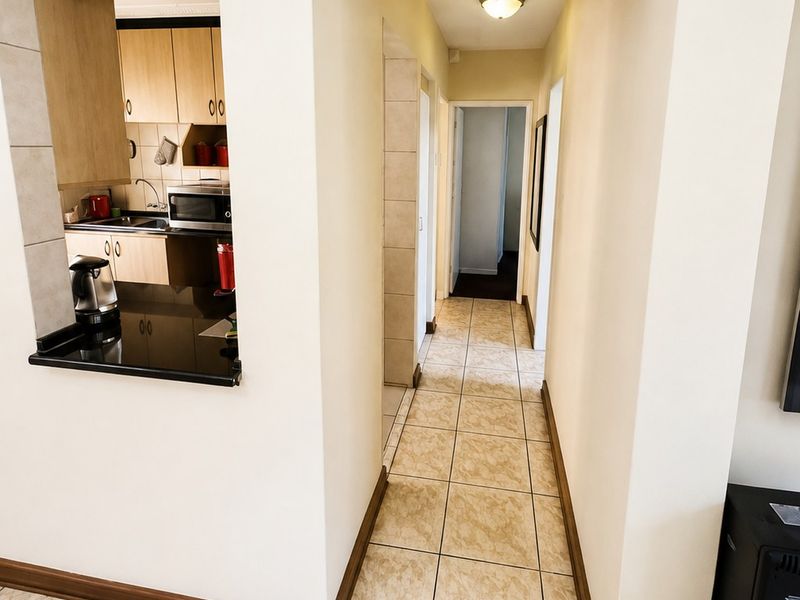 A bright hallway featuring tiled flooring and a convenient pass-through window connecting to the kitchen area, providing a functional layout for the home.