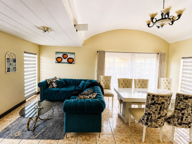 Spacious open-plan living and dining area featuring vaulted ceilings, tiled flooring, and large sliding glass doors providing ample natural light.