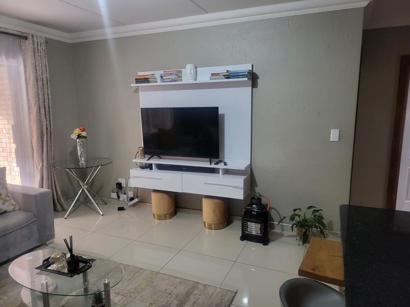 A living room featuring a modern white wall-mounted media console, neutral wall paint, and polished floor tiles.