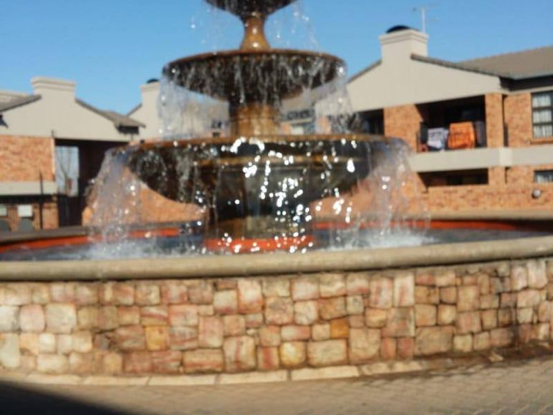 A multi-tiered stone water fountain located in a paved courtyard area within the apartment complex.