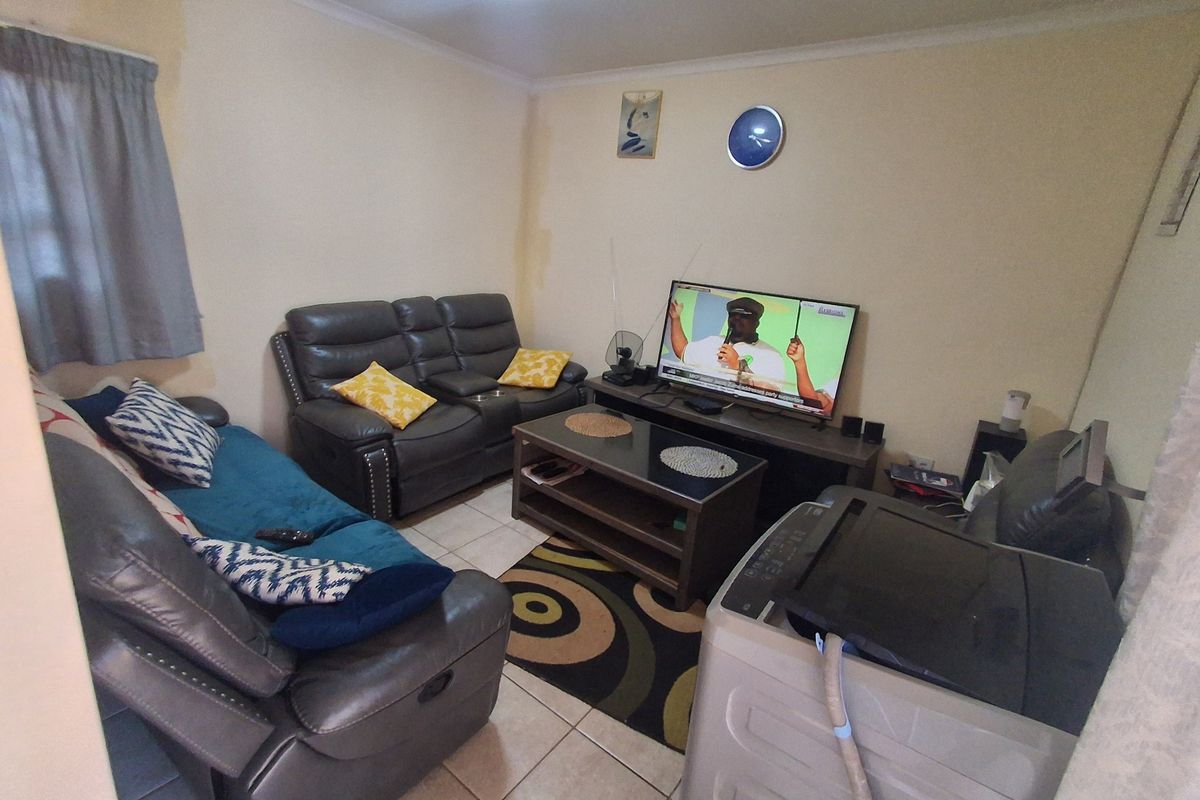 A compact living room featuring tiled flooring and coved ceilings, currently used as a multi-purpose space.