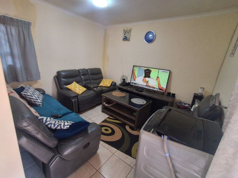A compact living room featuring tiled flooring and coved ceilings, currently used as a multi-purpose space.