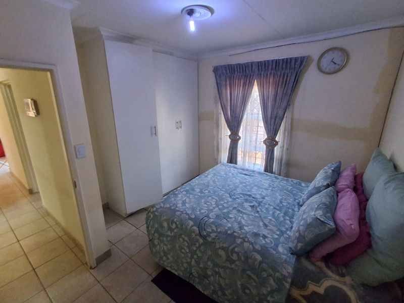 A bedroom featuring tiled flooring and a built-in wardrobe, currently showing signs of wall surface wear requiring maintenance or cosmetic updates.