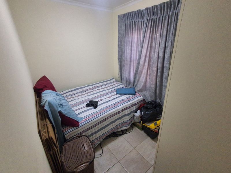 A compact bedroom featuring tiled flooring and window curtain rails, offering a functional space for a single bed.