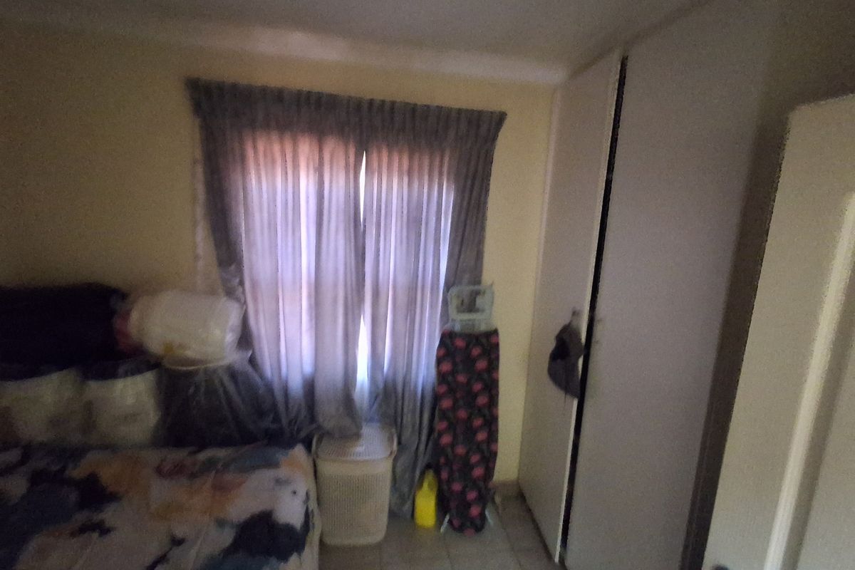 A bedroom featuring tiled flooring and a built-in wardrobe, providing functional storage space.