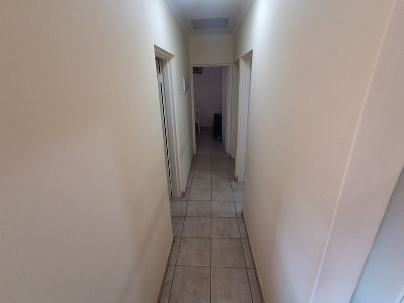 A functional interior hallway featuring neutral wall finishes and tiled flooring, providing access to multiple rooms within the home.