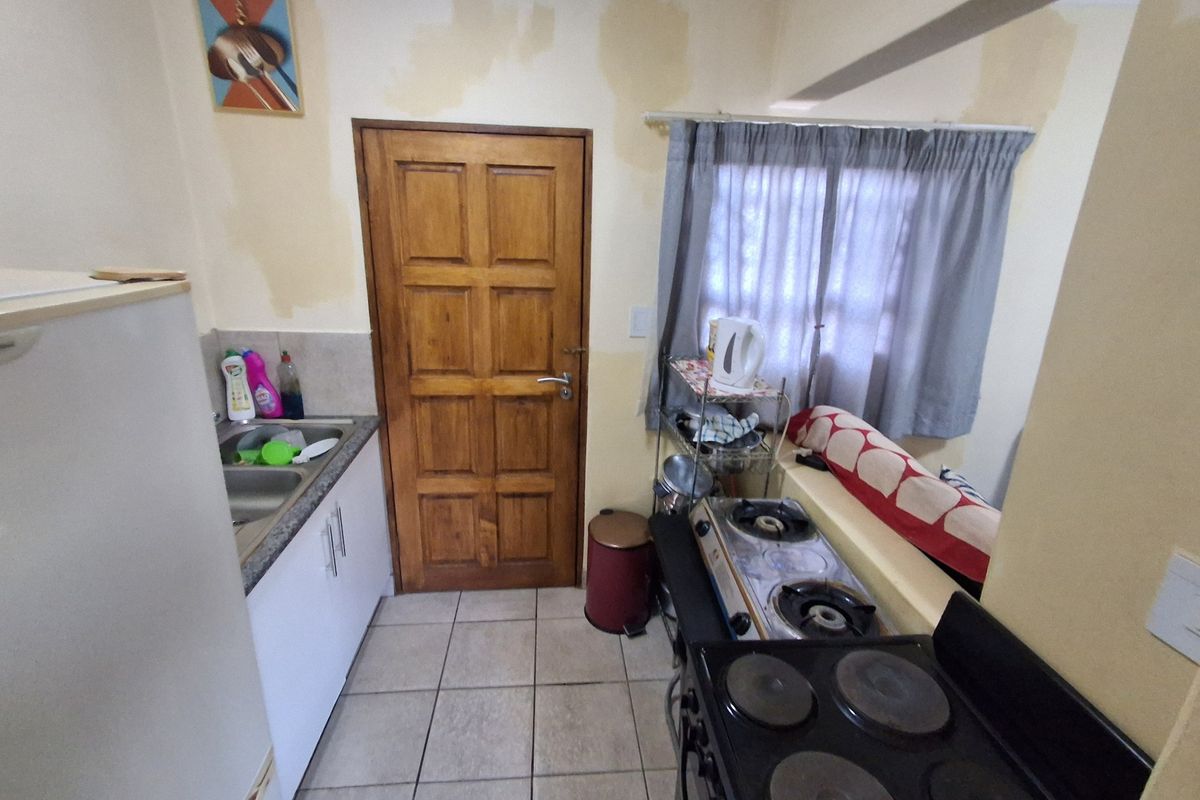 Compact kitchen featuring tiled flooring, granite countertops, and built-in cabinetry, currently showing signs of water damage on the walls requiring maintenance.
