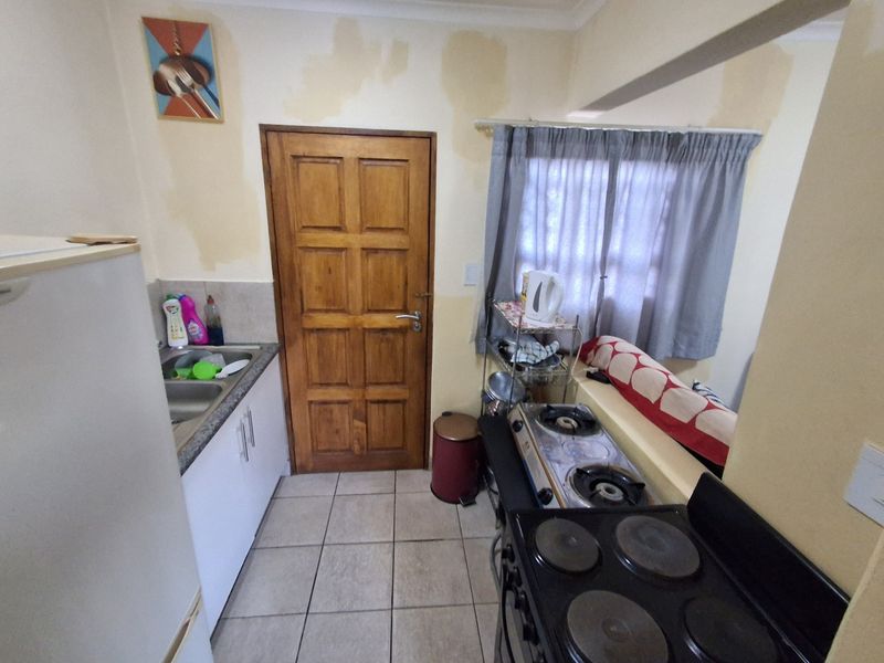 Compact kitchen featuring tiled flooring, granite countertops, and built-in cabinetry, currently showing signs of water damage on the walls requiring maintenance.