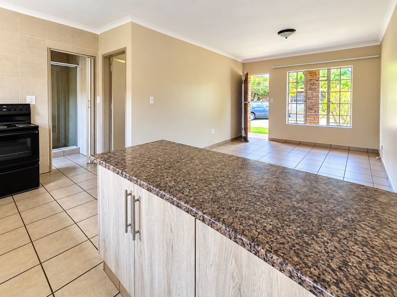 Open-plan living area featuring tiled flooring, a kitchen island with granite countertops, and direct access to the exterior.