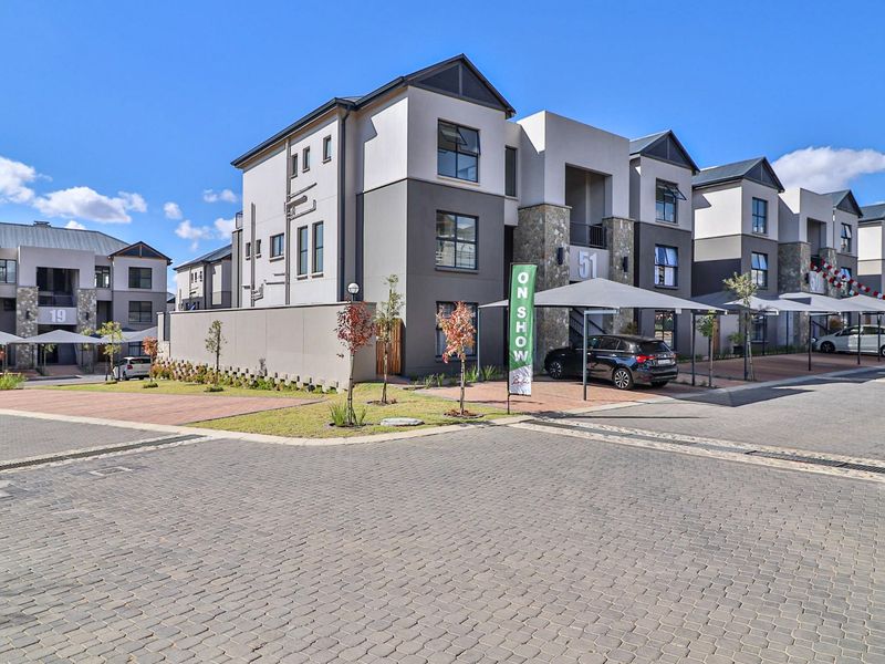 Modern apartment complex exterior featuring stone cladding, paved driveways, and covered parking bays in a well-maintained residential estate.