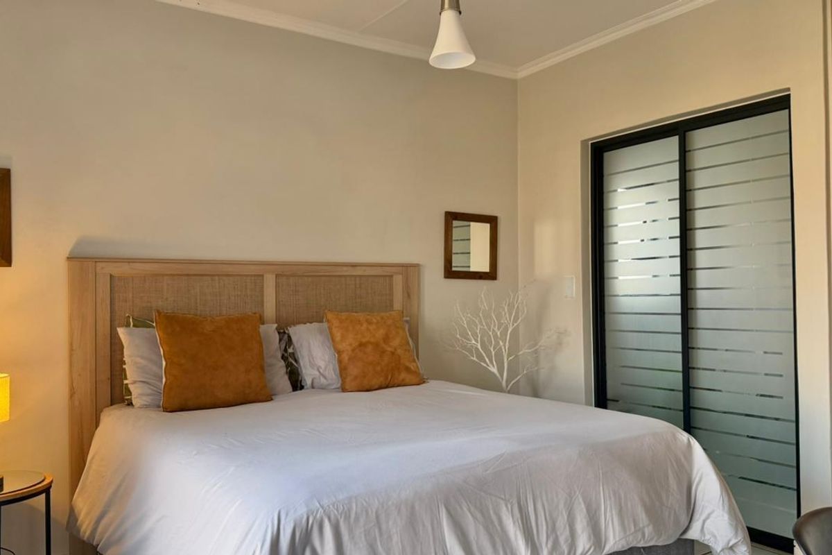 A well-maintained bedroom featuring a built-in sliding door wardrobe with frosted glass panels and neutral wall finishes.