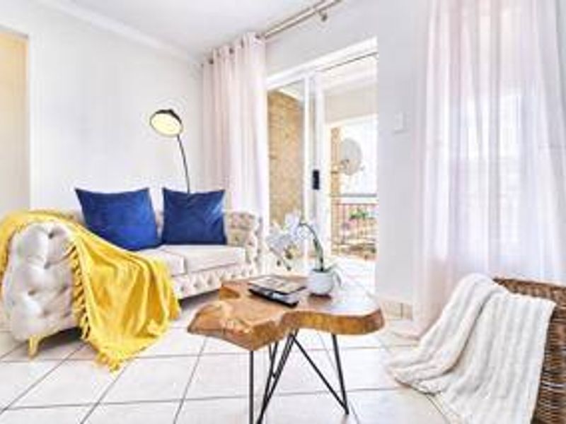 A bright living room featuring tiled flooring and a sliding glass door that provides access to an outdoor balcony area.