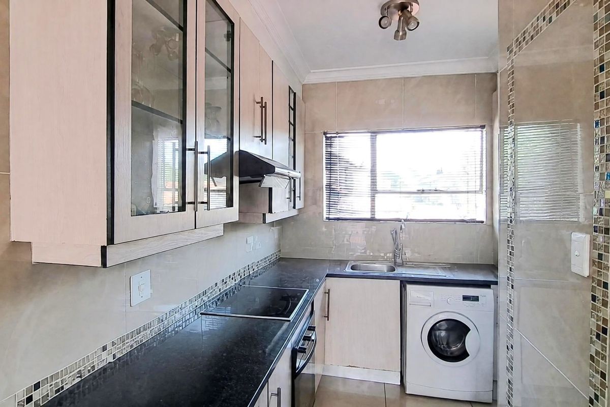 A functional kitchen featuring built-in cabinetry, granite countertops, a built-in oven and hob, and space for a washing machine.