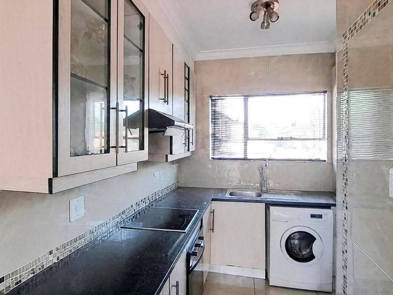 A functional kitchen featuring built-in cabinetry, granite countertops, a built-in oven and hob, and space for a washing machine.