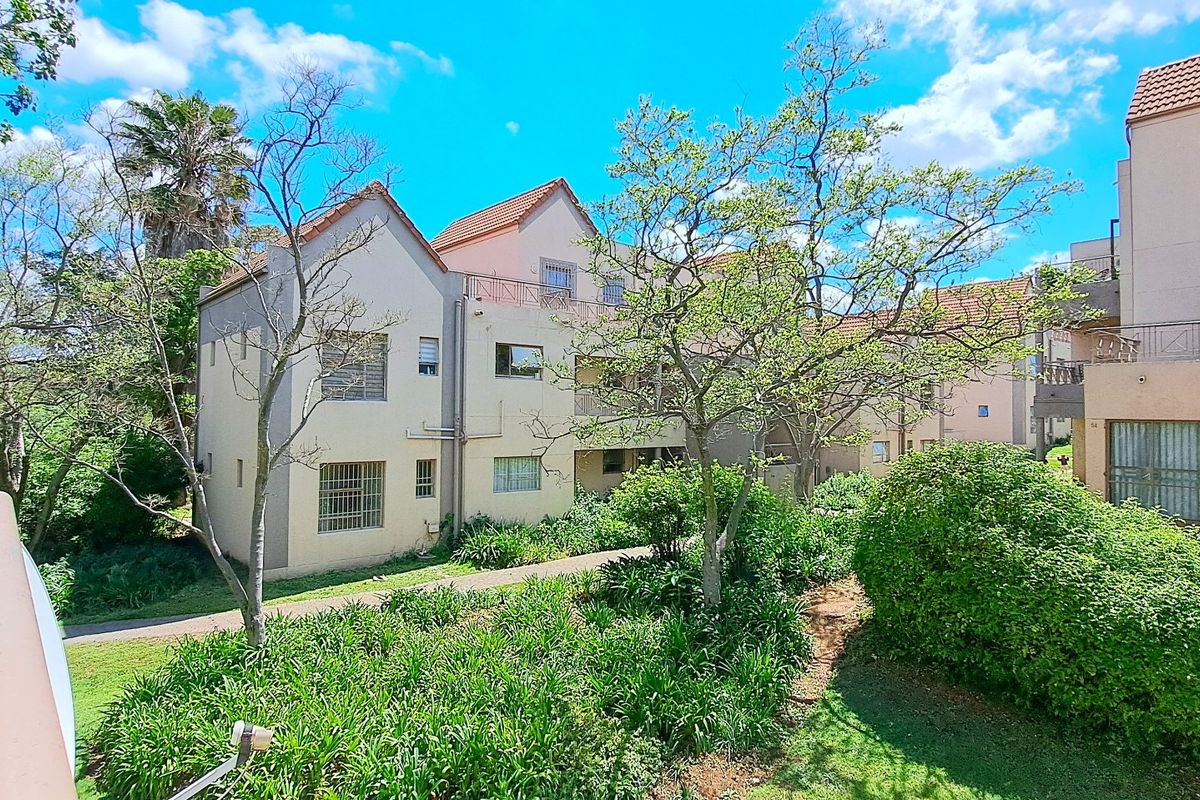 A view of the apartment complex exterior featuring tiled roofs, security-fitted windows, and well-maintained communal garden areas.