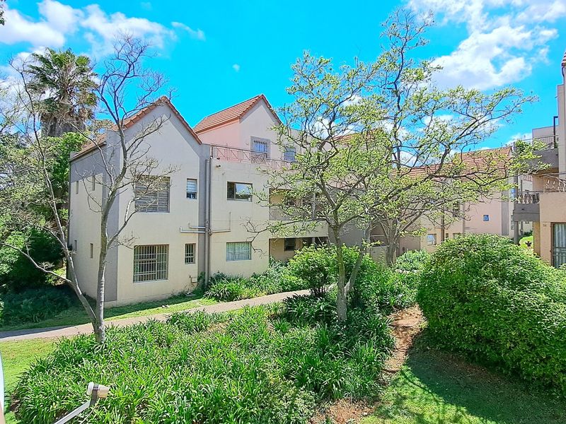 A view of the apartment complex exterior featuring tiled roofs, security-fitted windows, and well-maintained communal garden areas.