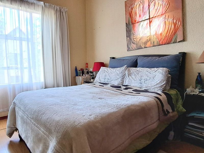 A standard bedroom featuring laminate flooring and large window with curtain tracks, providing natural light.