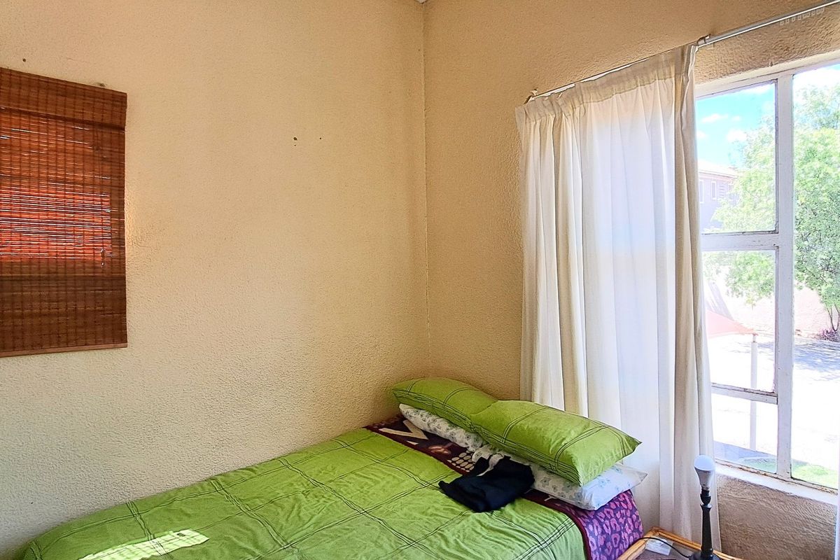 A bedroom featuring a large window with natural light and textured wall finishes, offering a blank canvas for potential renovation and modernization.