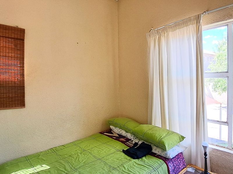 A bedroom featuring a large window with natural light and textured wall finishes, offering a blank canvas for potential renovation and modernization.