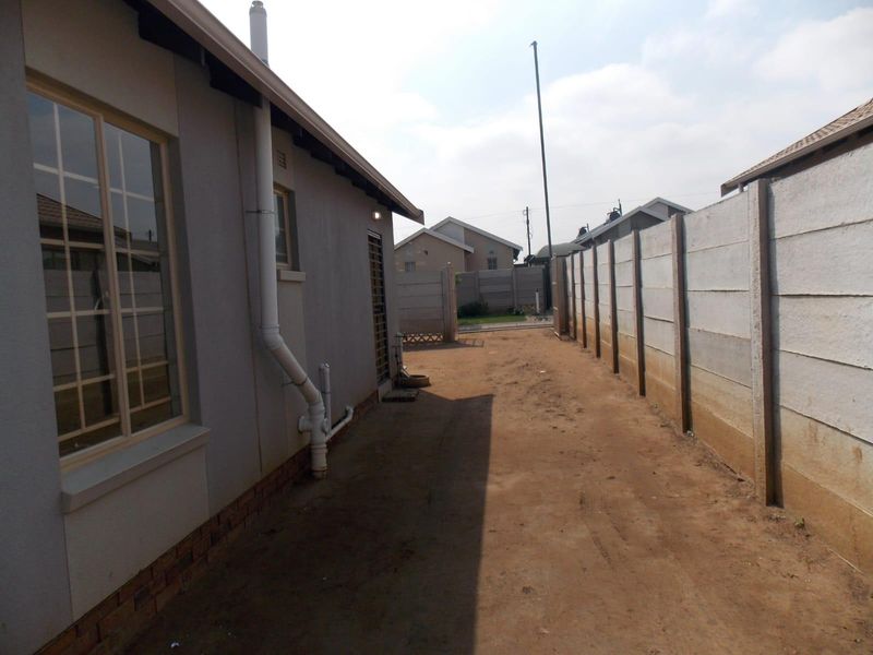 Side exterior view of the property featuring a precast concrete boundary wall and unlandscaped ground area.