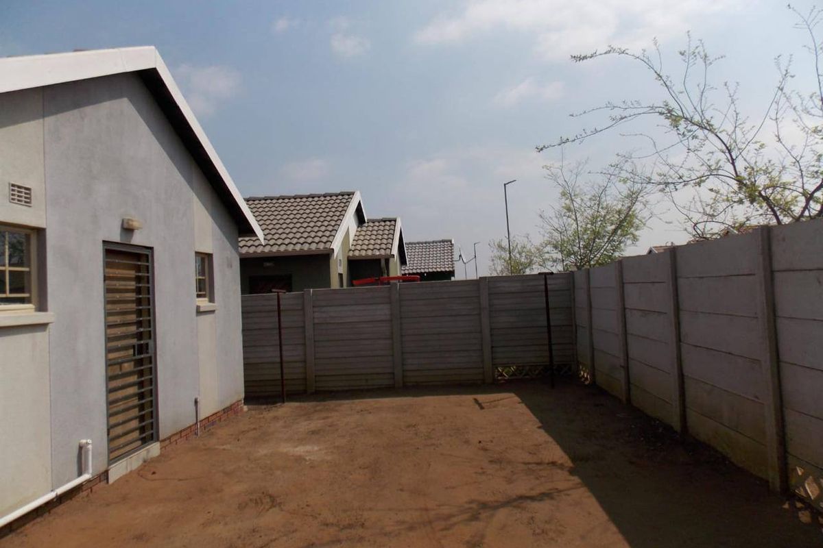 A private rear yard area featuring a precast concrete boundary wall and direct access to the home via a security gate.