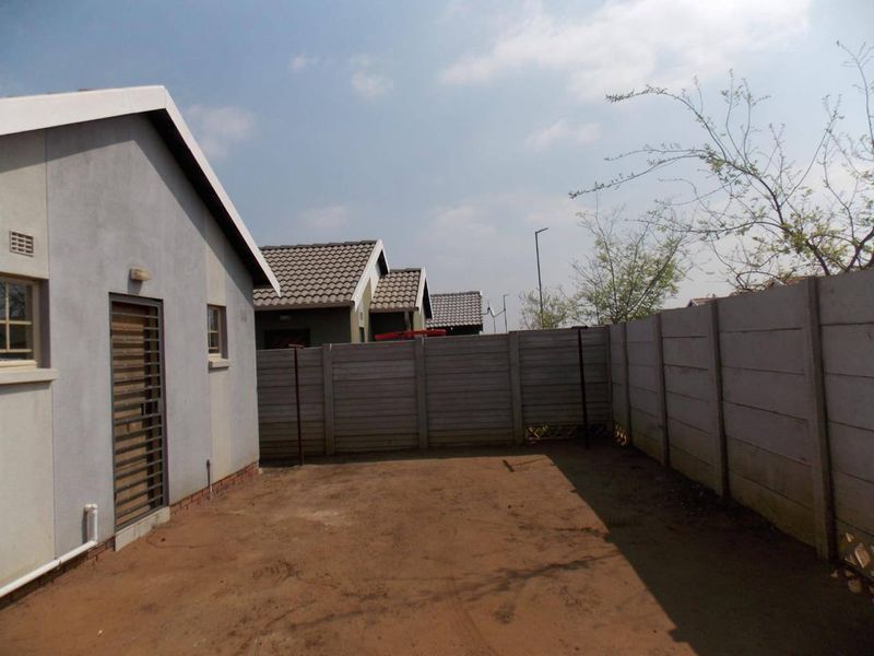 A private rear yard area featuring a precast concrete boundary wall and direct access to the home via a security gate.