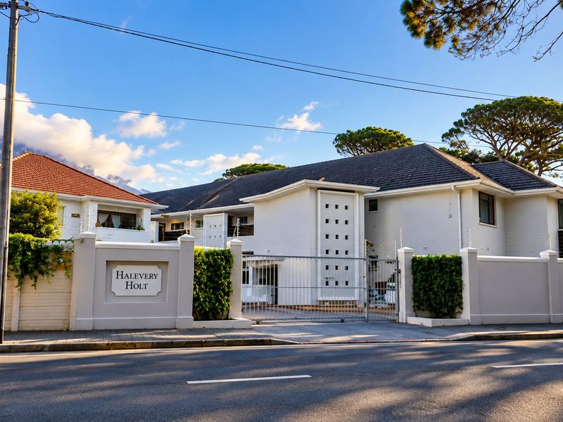 Front elevation of Halevery Holt apartment complex, featuring a secure gated entrance, perimeter wall with electric fencing, and well-maintained building facade.