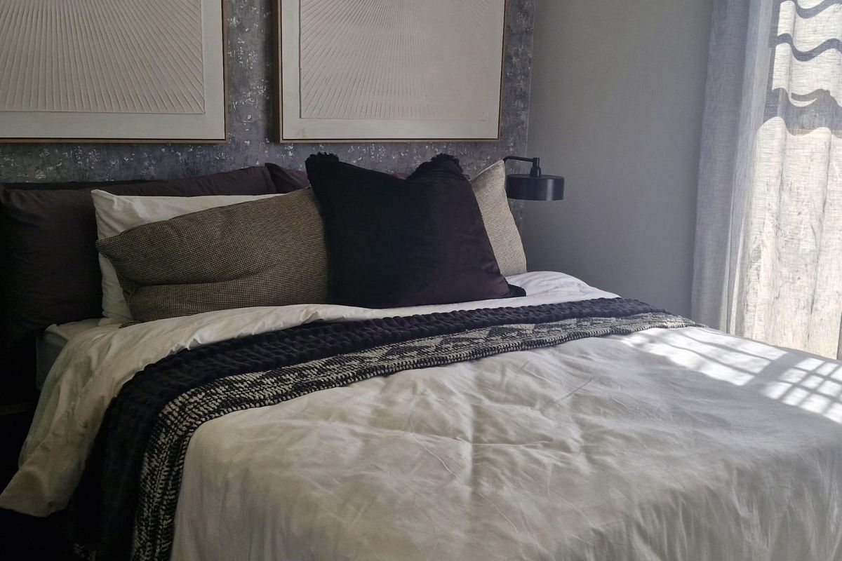 A well-appointed bedroom featuring a modern wall-mounted reading light and textured feature wall behind the bed area.