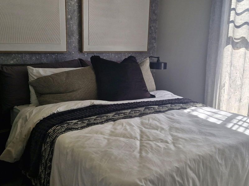 A well-appointed bedroom featuring a modern wall-mounted reading light and textured feature wall behind the bed area.