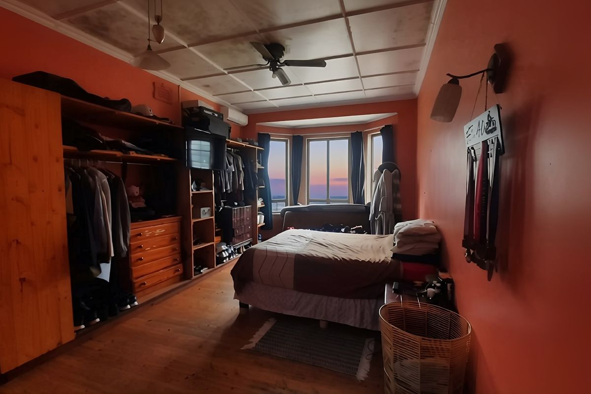 Bedroom featuring hardwood flooring, a ceiling fan, built-in wardrobe storage, and a bay window with natural light.