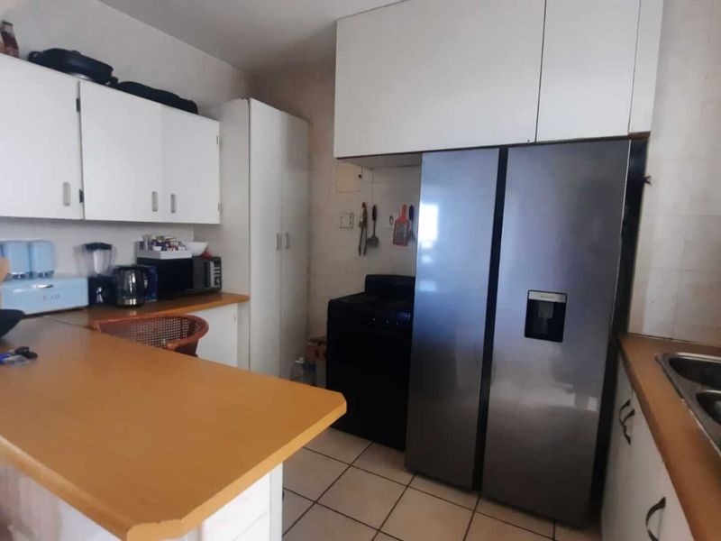 A functional kitchen featuring white cabinetry, laminate countertops, a double basin sink, and tiled flooring, providing a practical layout for daily meal preparation.