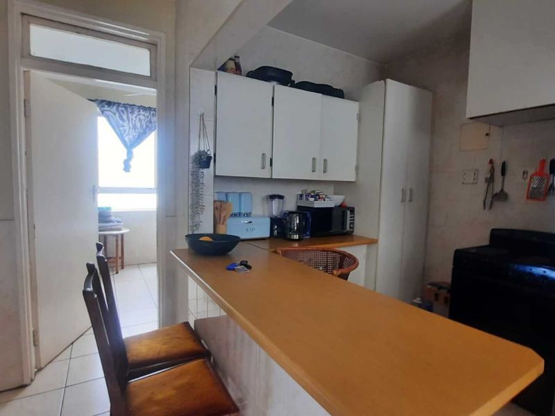 A functional kitchen featuring built-in cabinetry, a breakfast bar, and tiled flooring, offering potential for modernization and aesthetic updates.
