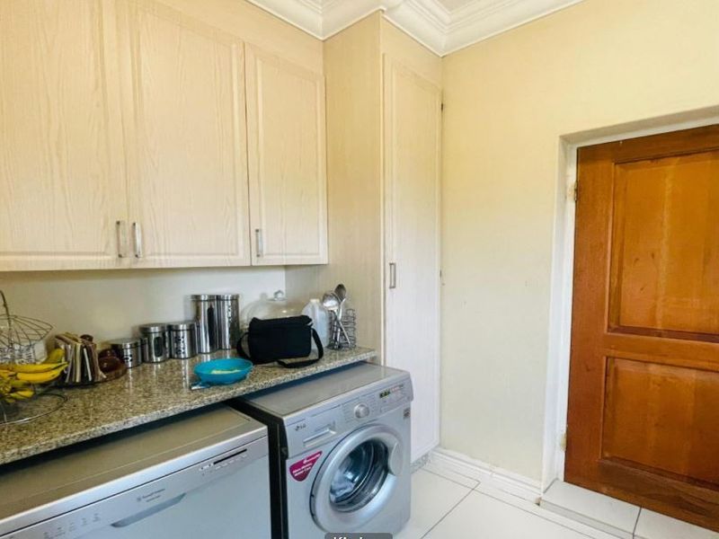 A functional laundry area featuring built-in cabinetry, granite countertops, and tiled flooring, providing practical utility space with direct access to an exterior door.