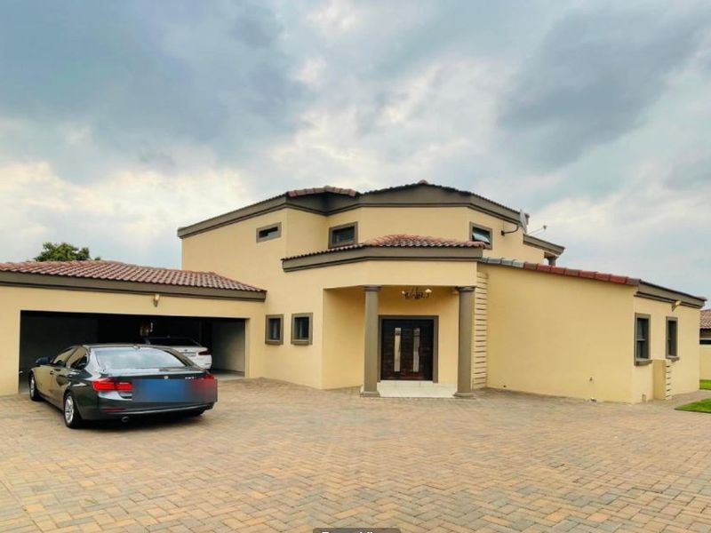 A well-maintained double-story residential property featuring a paved driveway, double garage, and a covered entrance with architectural columns.