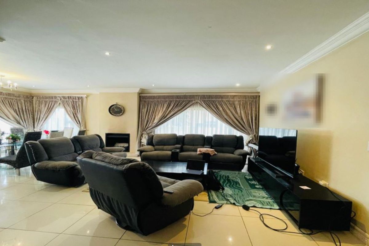Spacious living room featuring tiled flooring, recessed lighting, crown molding, and a built-in fireplace, creating a comfortable and well-defined lounge area.
