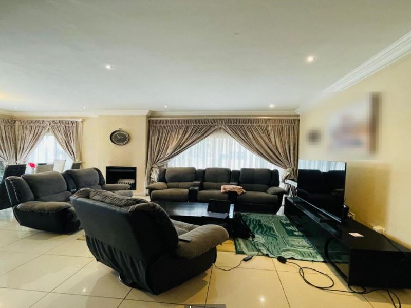 Spacious living room featuring tiled flooring, recessed lighting, crown molding, and a built-in fireplace, creating a comfortable and well-defined lounge area.