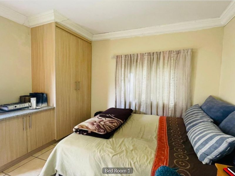 A bedroom featuring built-in wooden cabinetry, tiled flooring, and crown molding, providing functional storage and a neutral base for interior design.