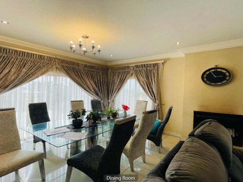 A well-lit dining room featuring tiled flooring, a built-in fireplace, and large sliding glass doors with elegant drapery.
