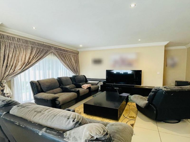A spacious living room featuring tiled flooring, recessed downlighting, and large sliding glass doors with curtain treatments.