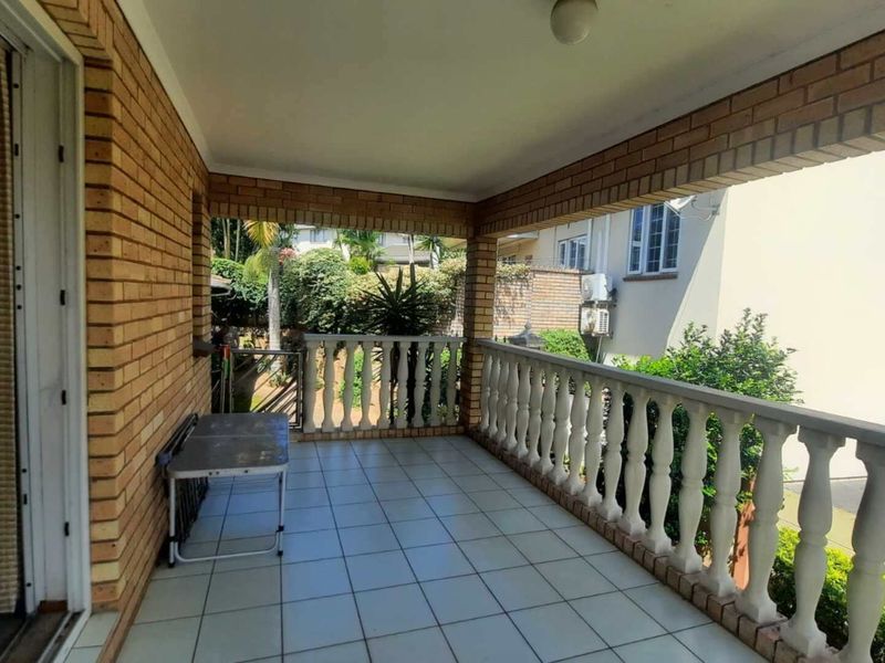 A covered balcony featuring tiled flooring and a classic balustrade, offering an outdoor space suitable for relaxation or entertaining.