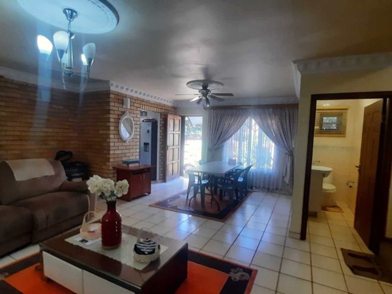 Spacious open-plan living and dining area featuring exposed brick accents, tiled flooring, and direct access to the exterior.