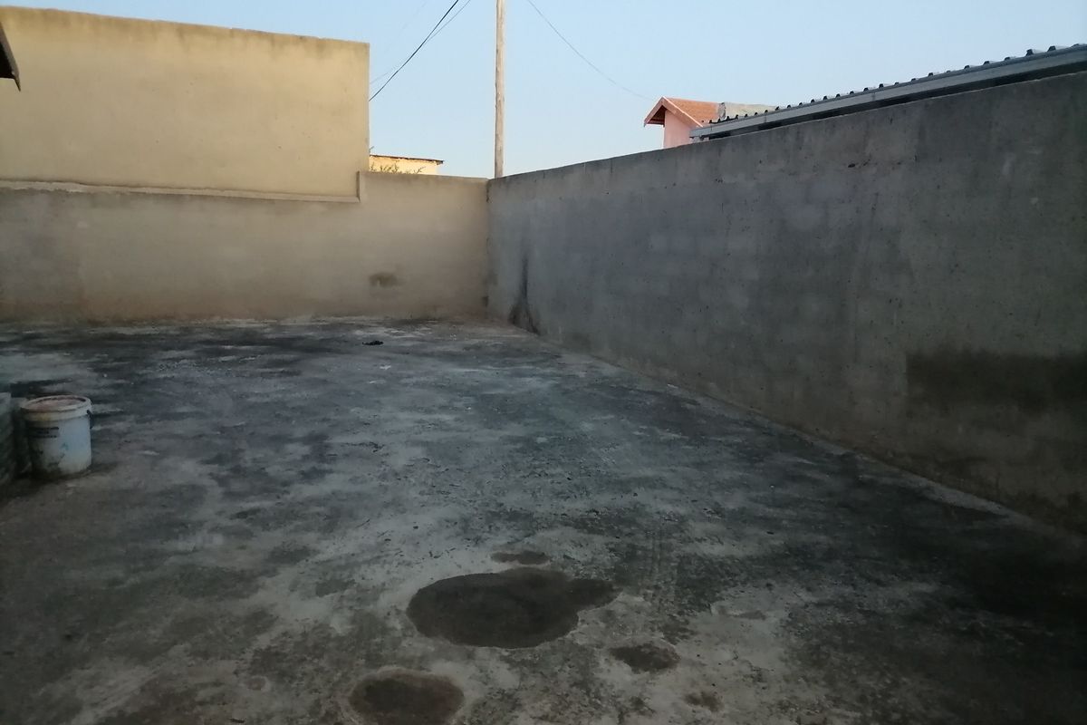 An open, paved rear yard area enclosed by concrete boundary walls, offering a blank canvas for landscaping or outdoor development.