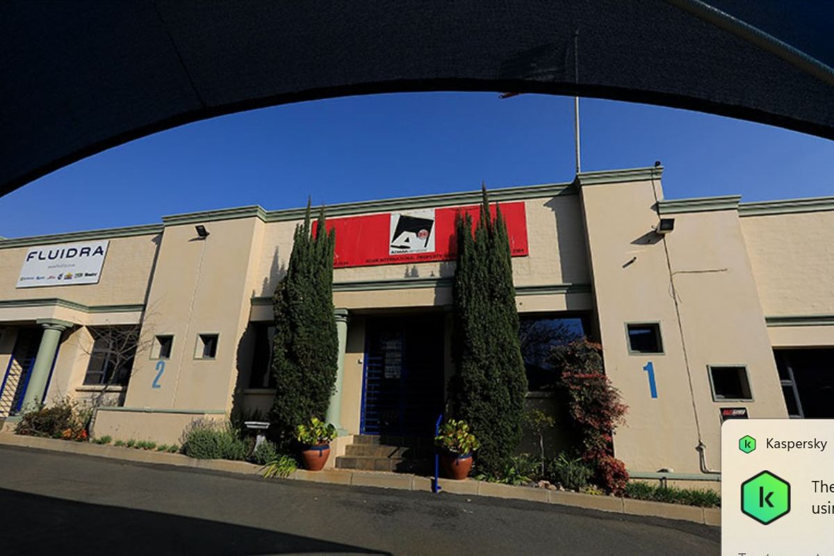 Front elevation of a commercial property featuring a paved driveway, entrance steps, and prominent signage.