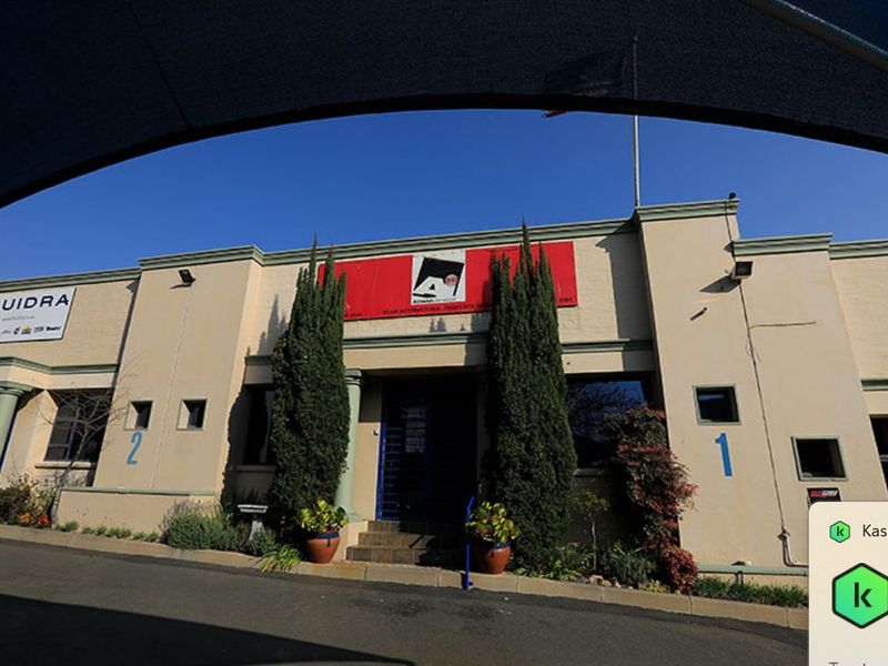 Front elevation of a commercial property featuring a paved driveway, entrance steps, and prominent signage.