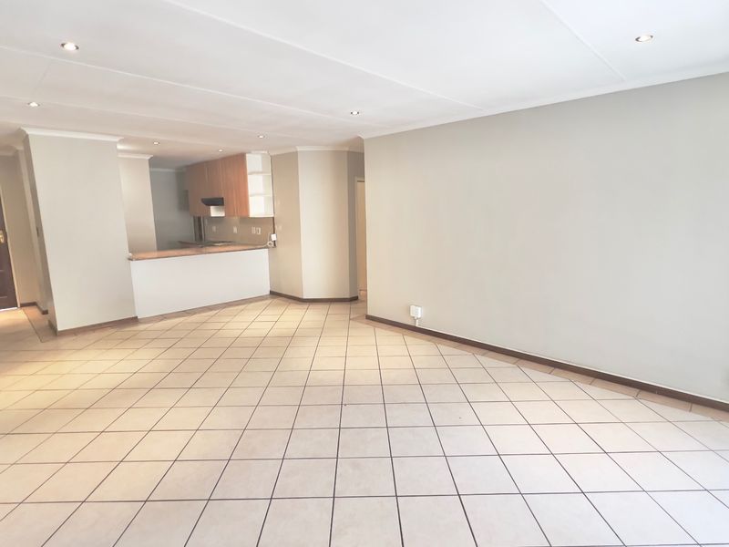 Spacious open-plan living area featuring ceramic tiled flooring, recessed lighting, and a functional kitchen with breakfast bar and built-in cabinetry.