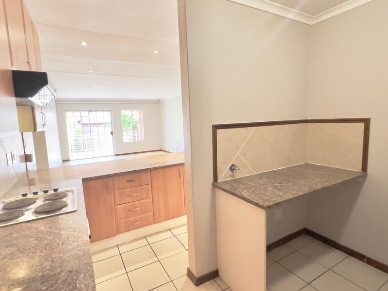 Open plan kitchen and utility area featuring built-in cabinetry, electric hob, extractor fan, and tiled flooring, offering a functional layout for modern living.